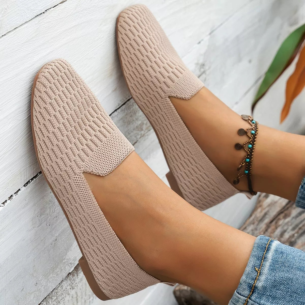 Beige knitted shoes worn with a white wooden floor background