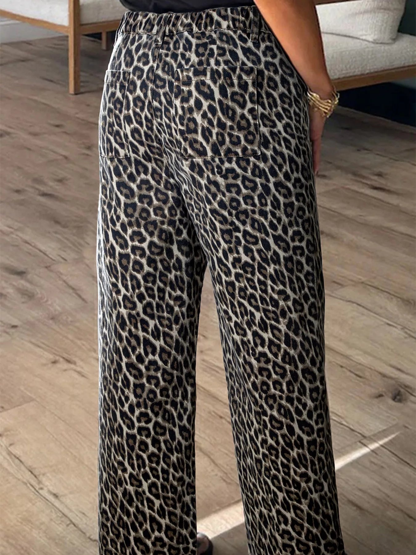 Leopard print pants worn by a person on a wooden floor.
