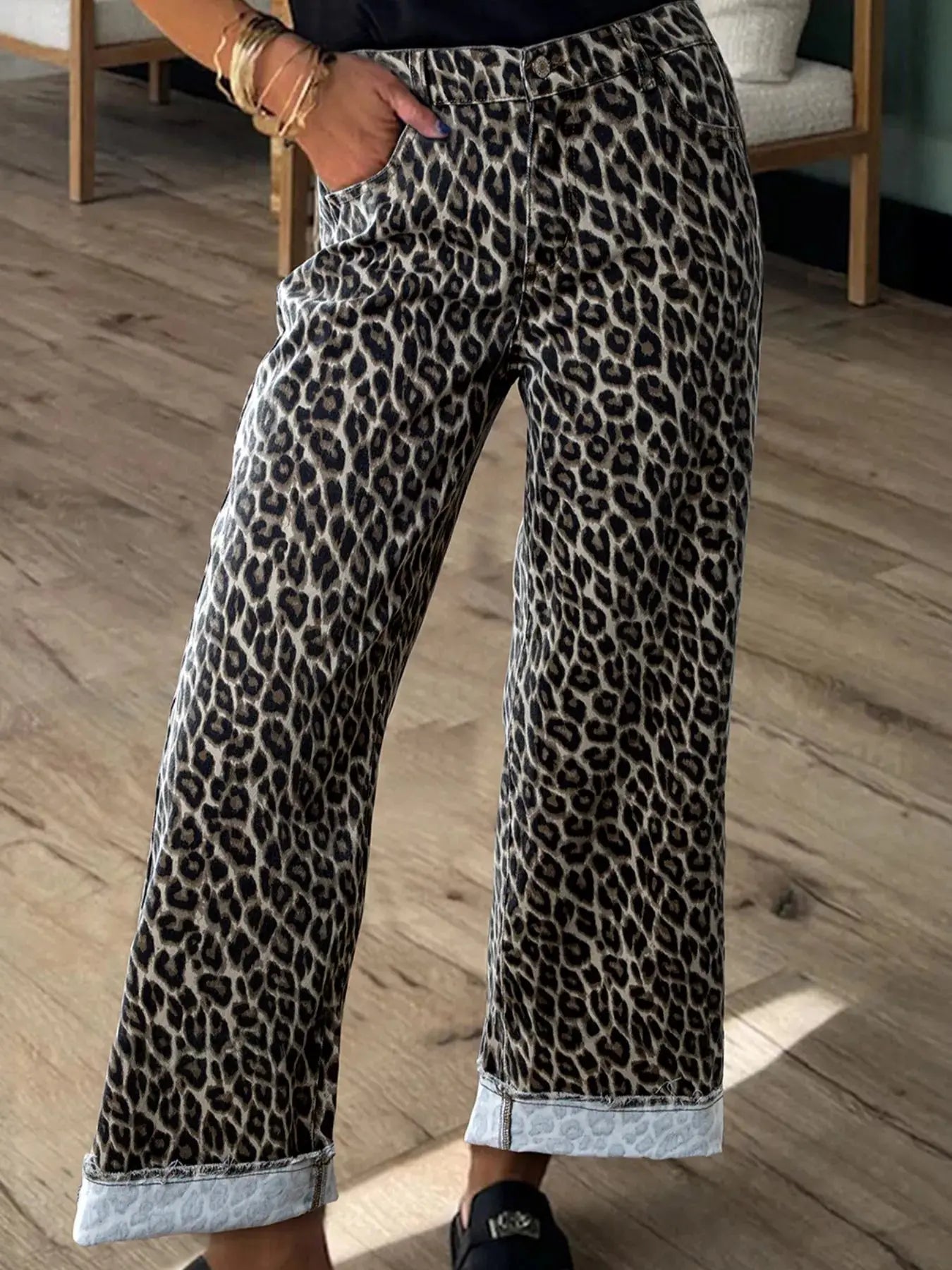 Leopard print pants worn by a person on a wooden floor.