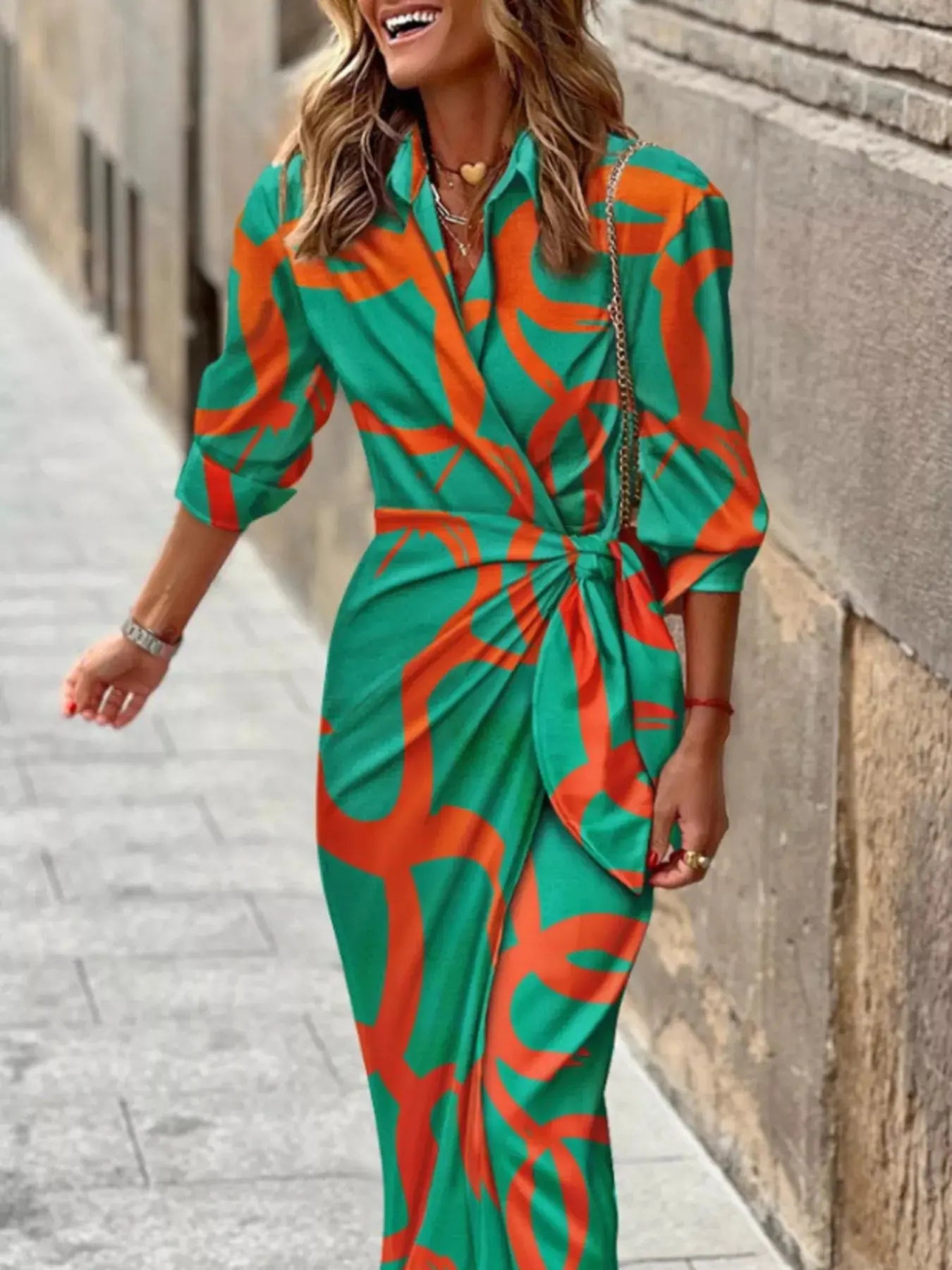 Woman wearing a green and orange patterned outfit walking on a street.