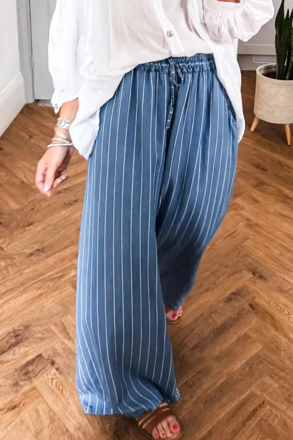 person wearing blue striped pants and a white shirt on a wooden floor.